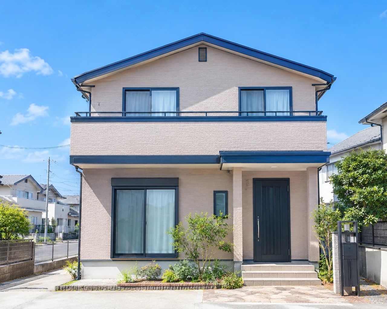 塗り替えた直後の2階建ての家。灰桜色の外壁に、鉄紺色の帯